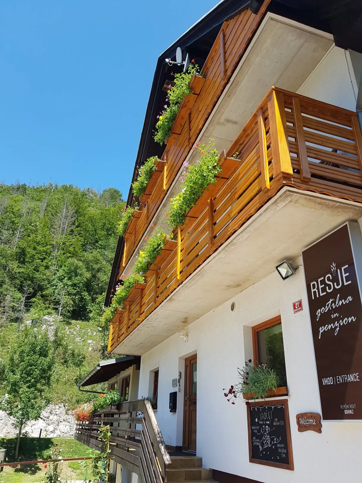 Façade blanche et balcons de bois fleuris de la pension