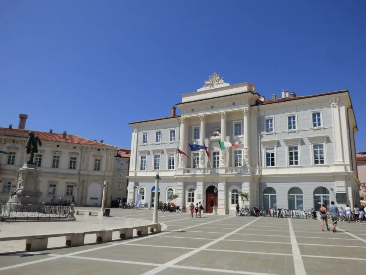 Hôtel de ville blanc et statue du violoniste, drapeaux au vent