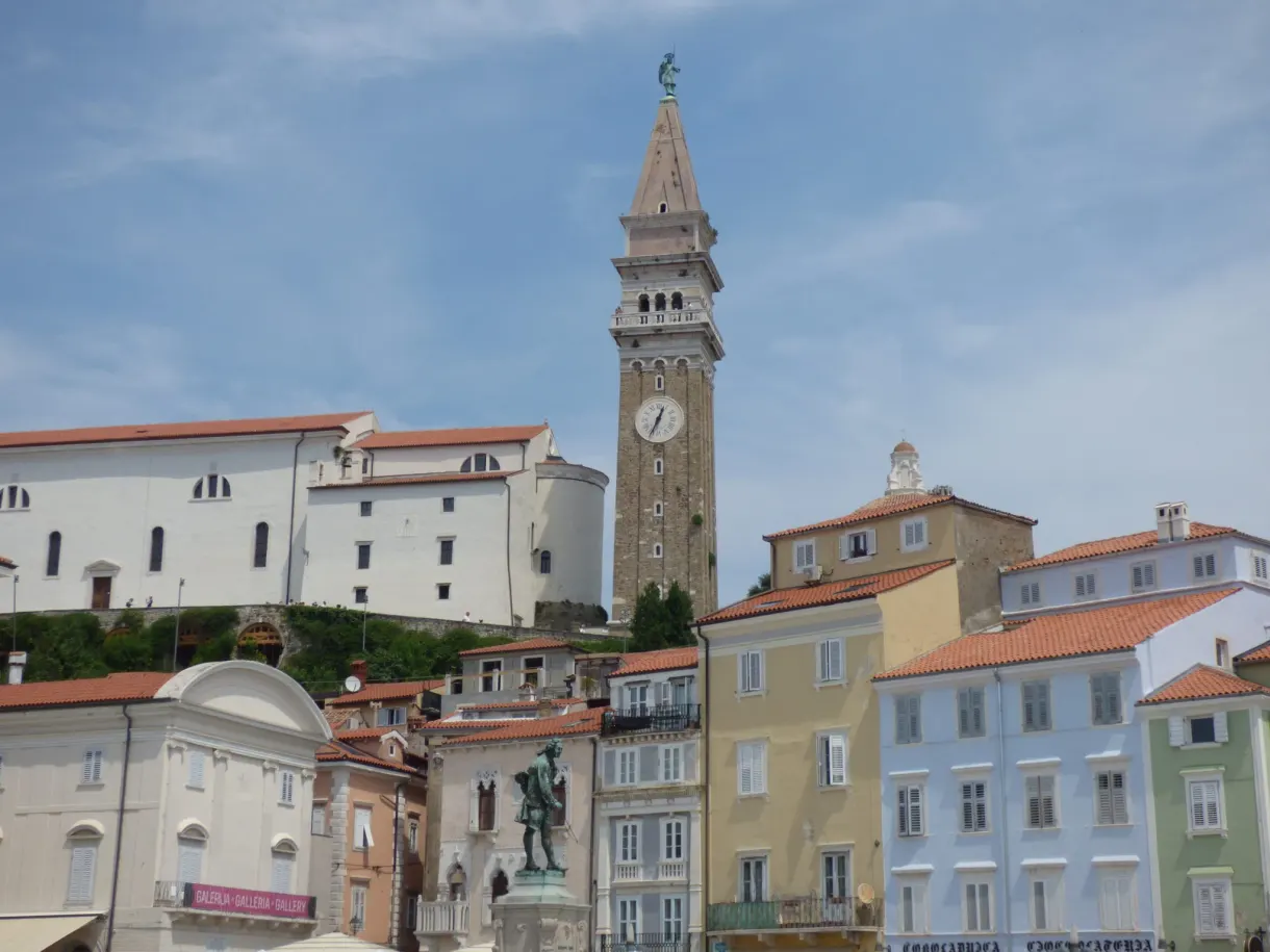 Campanile de pierre dominant les maisons pastel de la place
