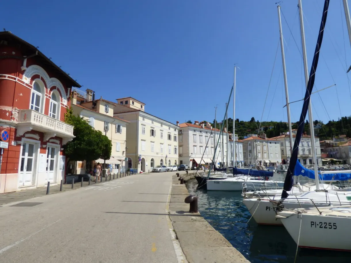 Quai du port longé de voiliers, maison d'angle rouge vif
