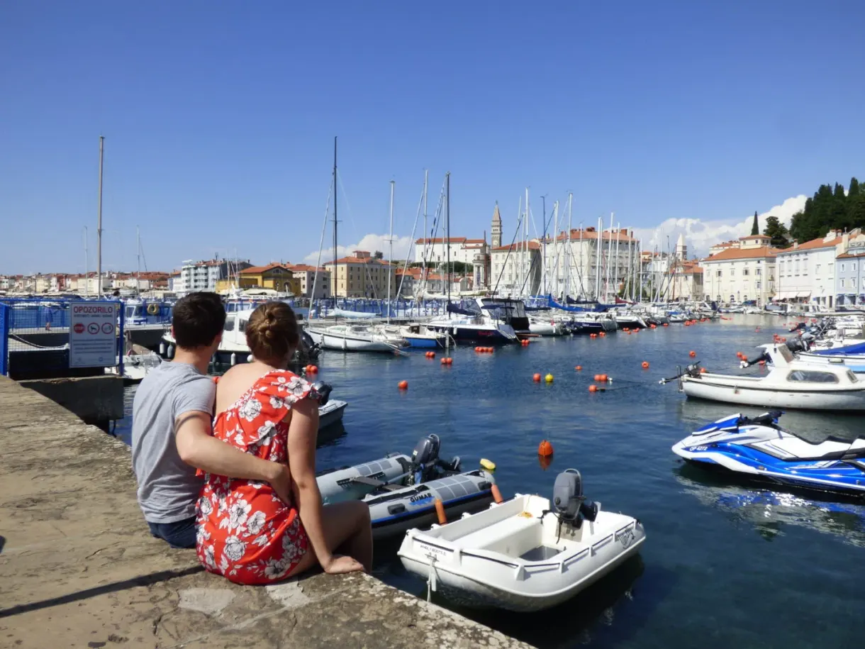 Couple assis sur le muret face aux bateaux du port