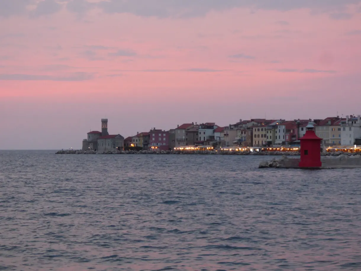 Phare rouge et silhouette de la vieille ville au soir