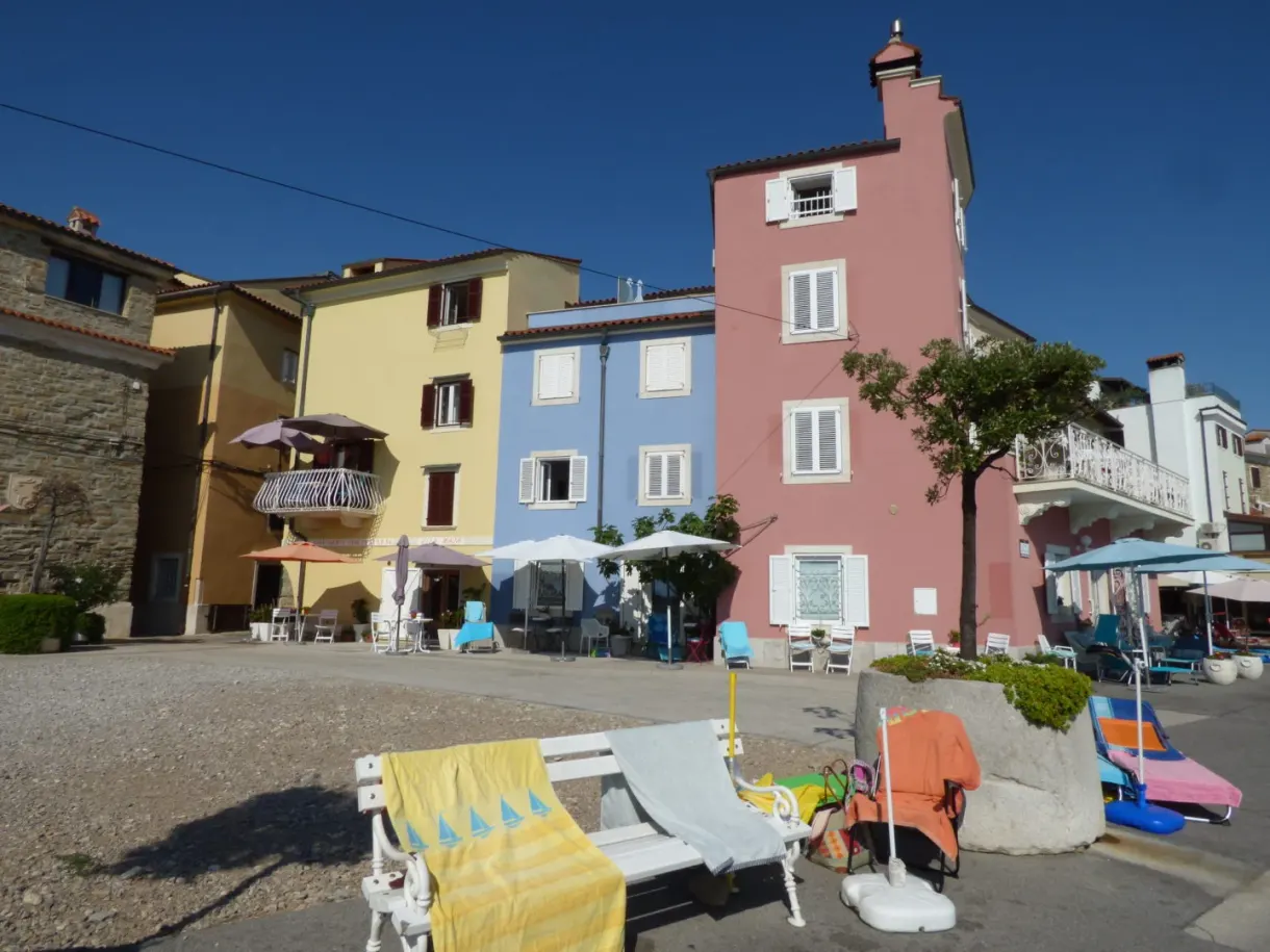 Maison rose et transats sur une placette au bord de l'eau