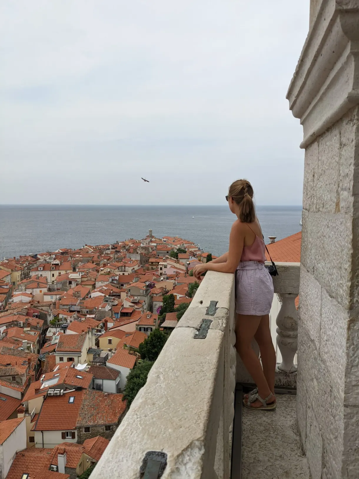 Jeune femme accoudée au parapet au-dessus des toits de tuiles