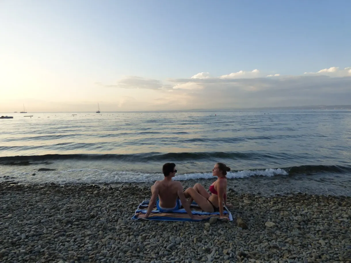 Deux baigneuses assises sur les galets au soleil couchant