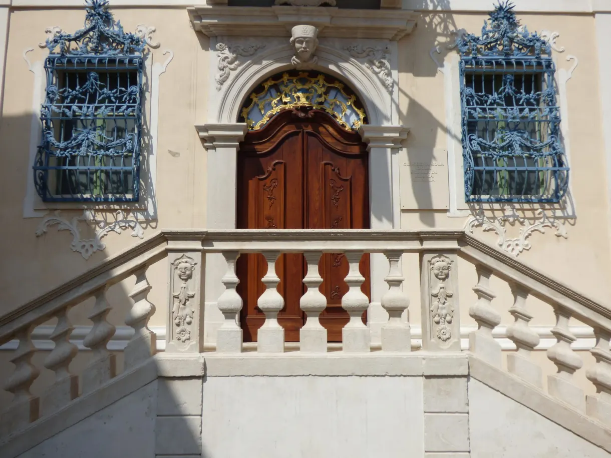 Portail baroque à balustrade encadré de grilles bleu ciel