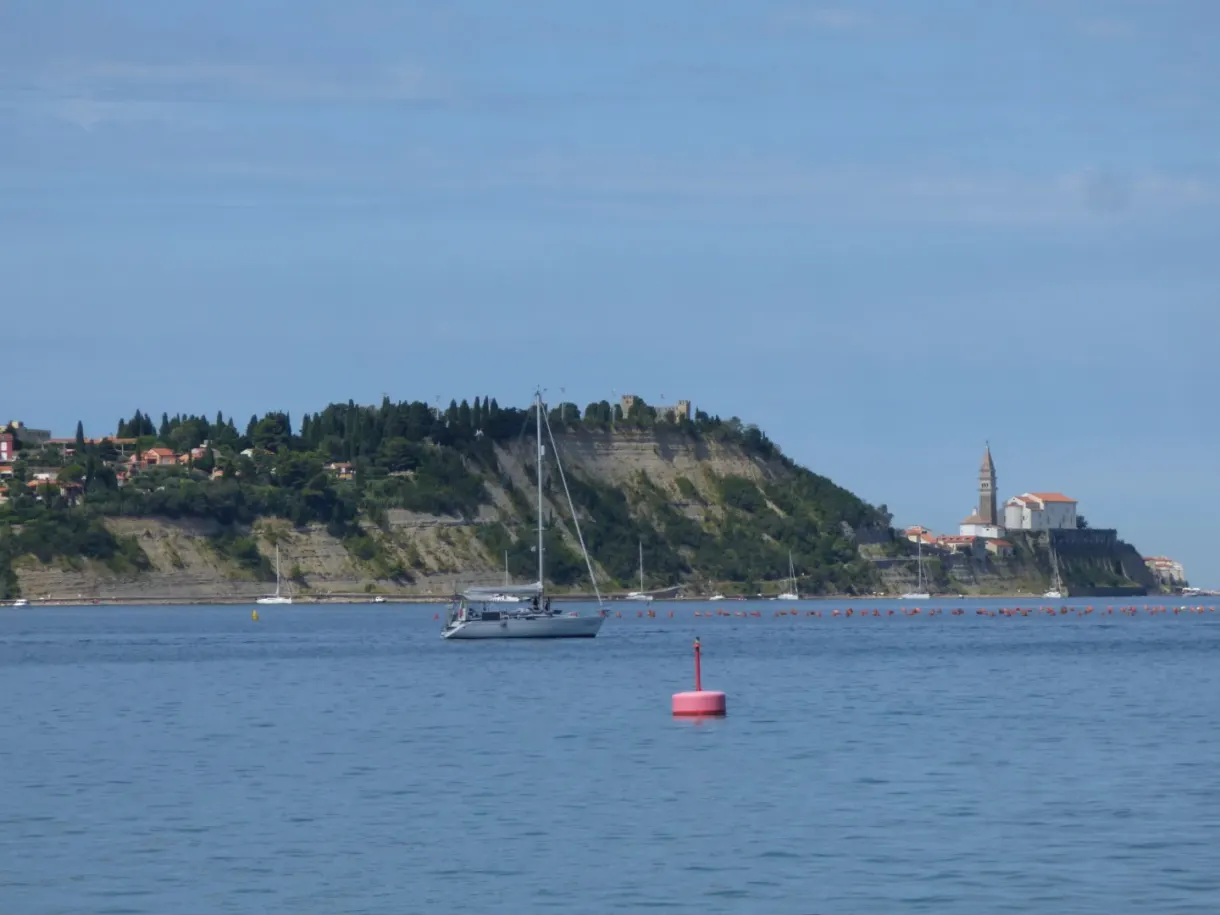 Voilier au mouillage devant la presqu'île et son clocher
