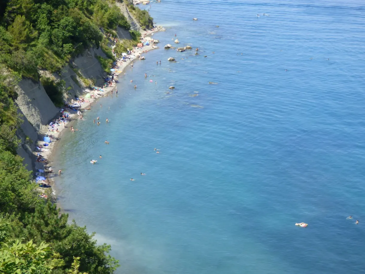 Plage de galets au pied de la falaise, eau limpide