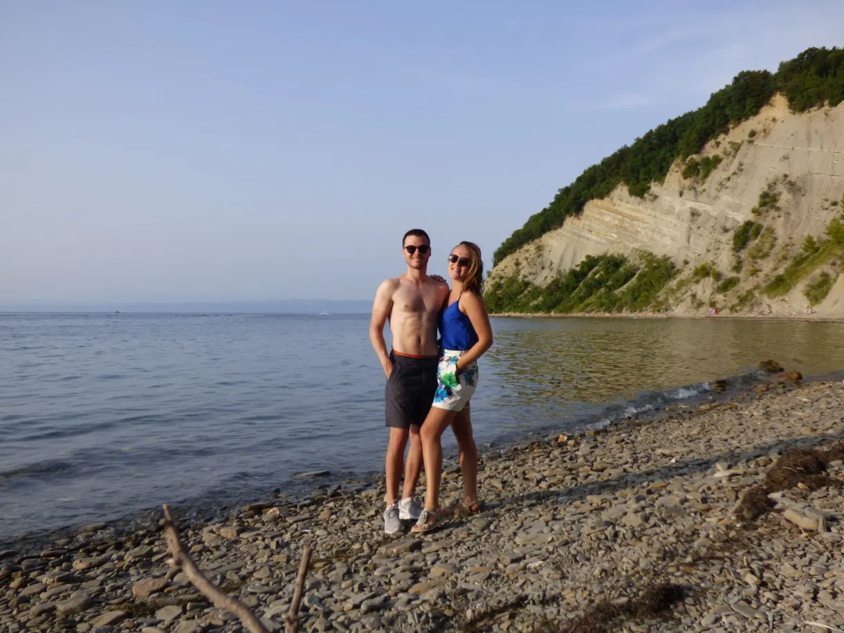 Couple posant sur les galets sous la falaise ocre