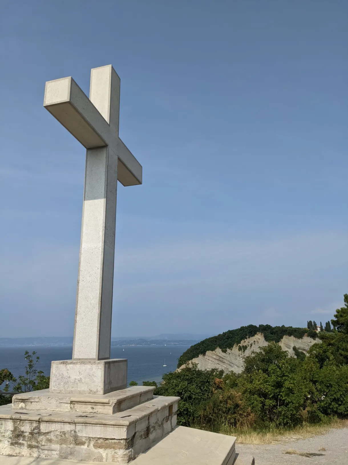 Grande croix blanche dressée sur un socle face à la mer