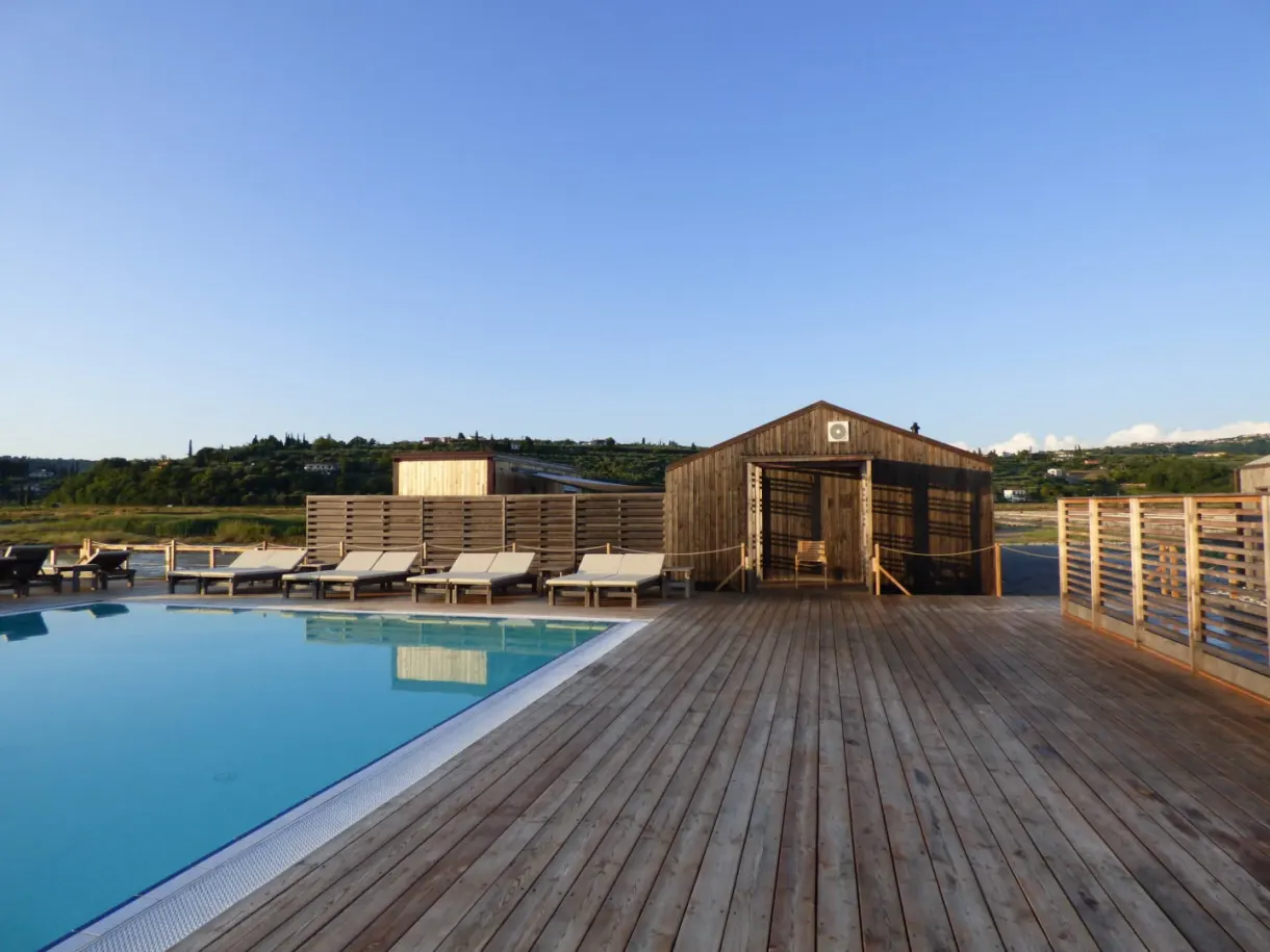 Piscine bordée de transats devant une cabane de bois brut
