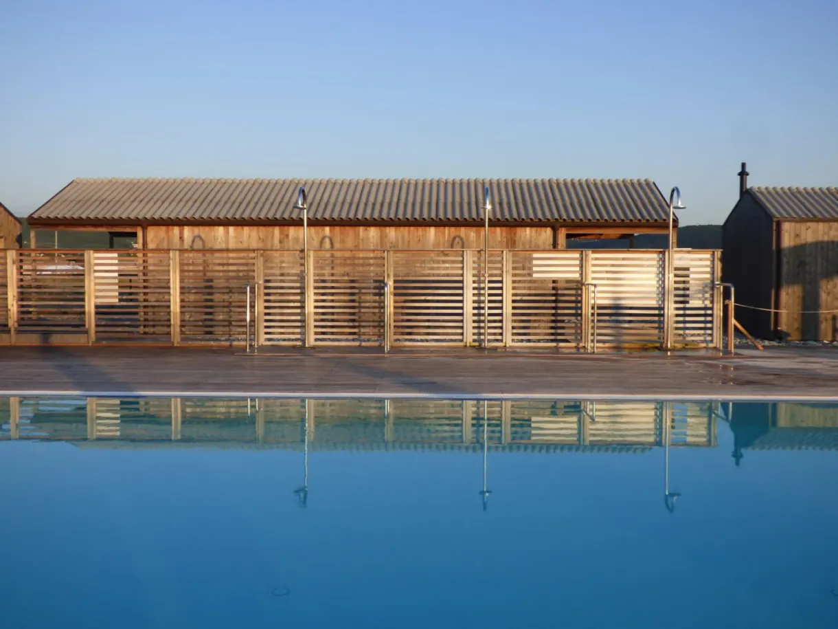 Longue piscine miroir courant devant les cabanes de bois