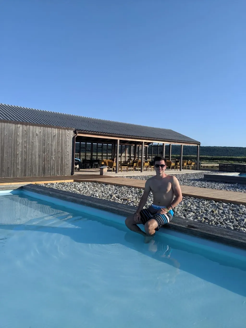 Baigneur assis sur le rebord de la piscine devant le pavillon