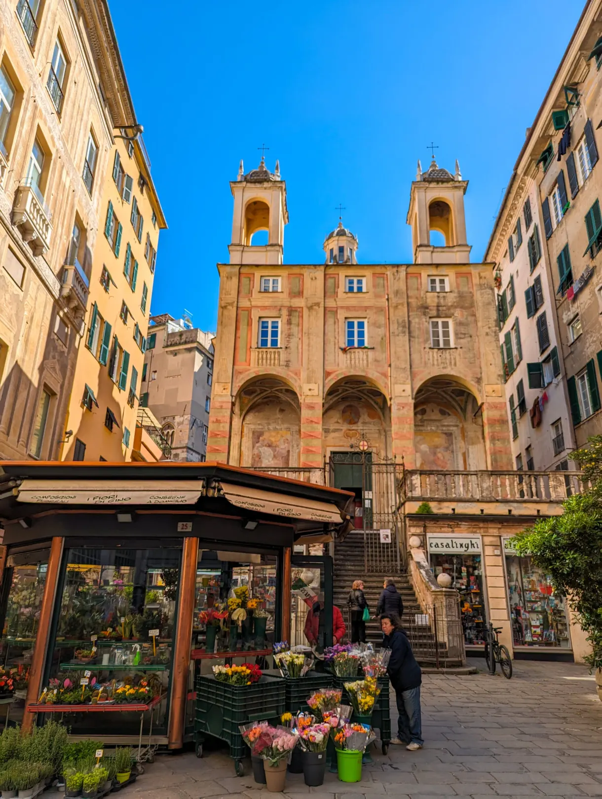 Kiosque de fleuriste devant un palais à arcades sur une place génoise