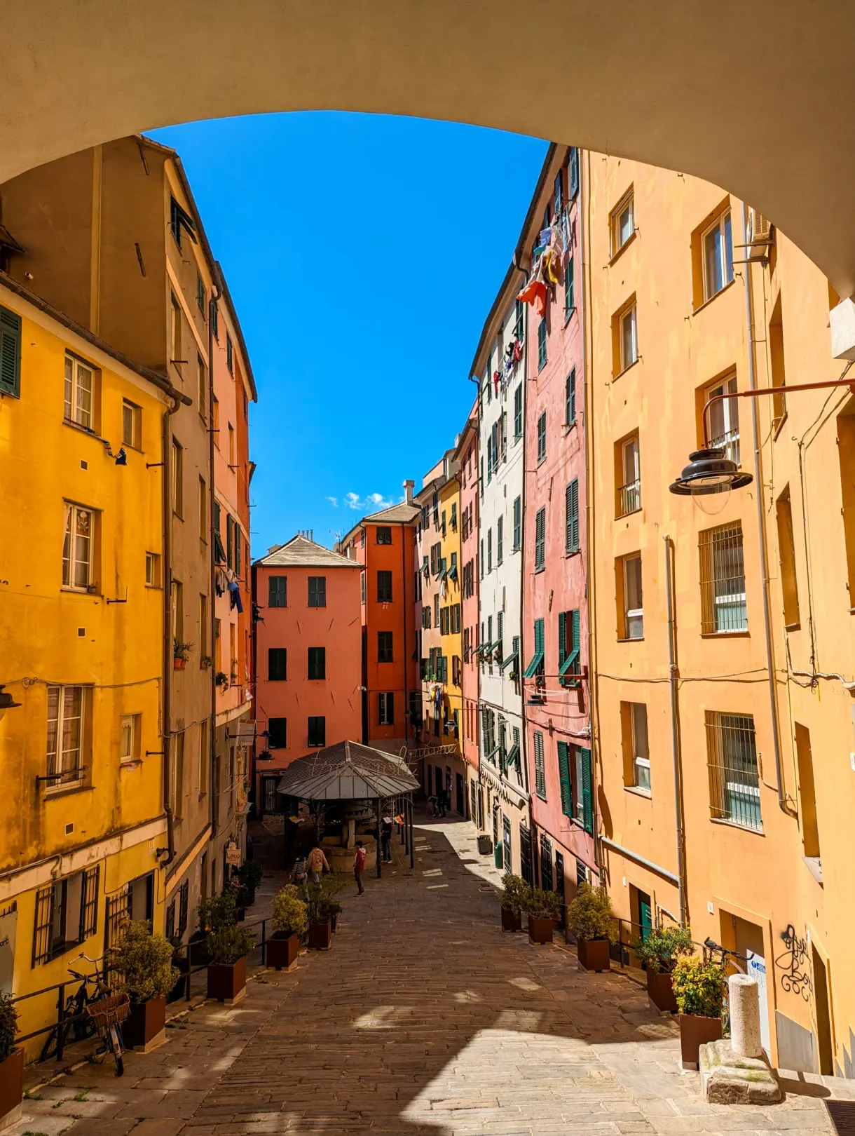 Arche de pierre ouvrant sur une ruelle aux façades colorées