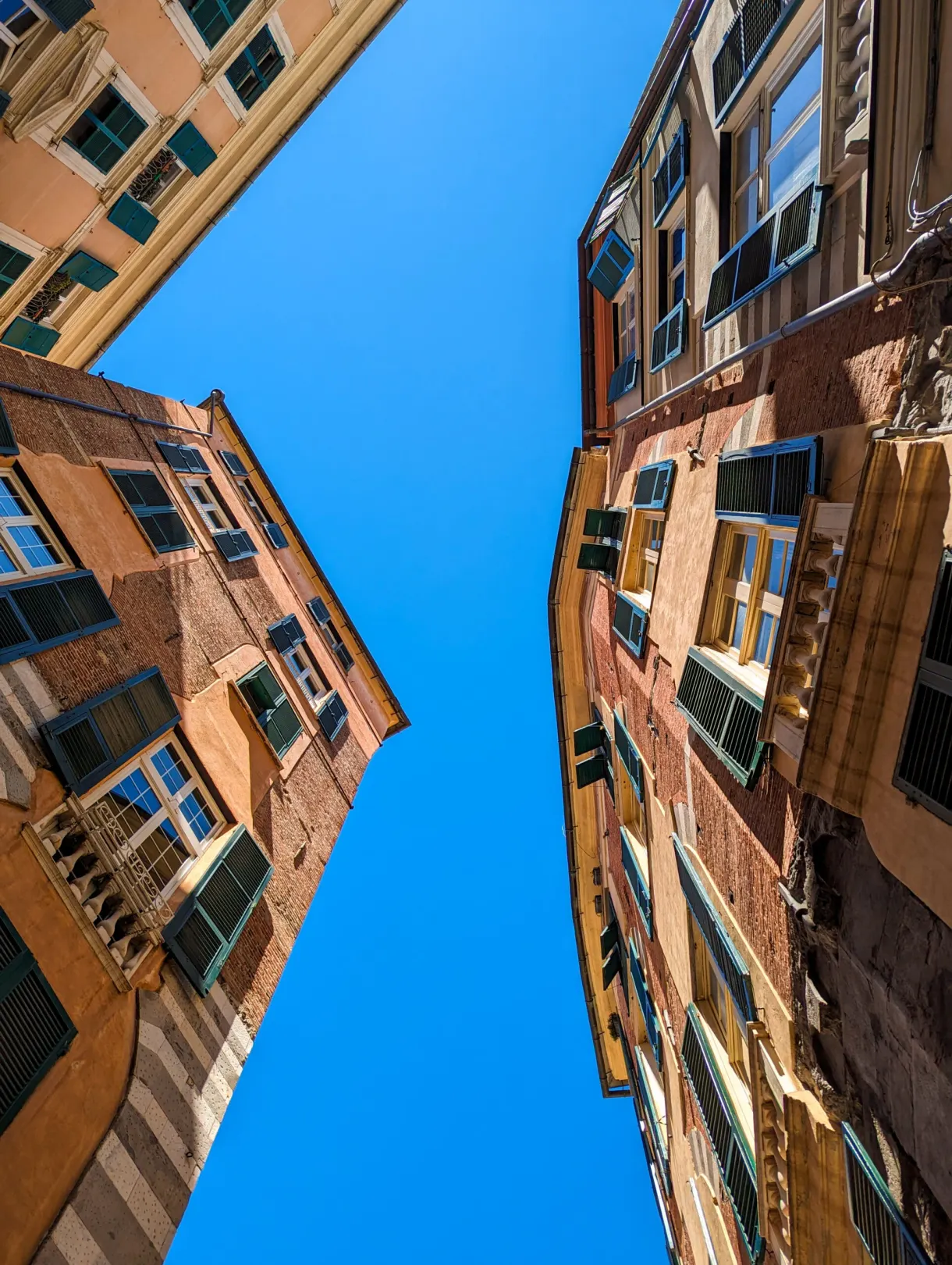 Contre-plongée entre deux hauts immeubles anciens vers le ciel bleu