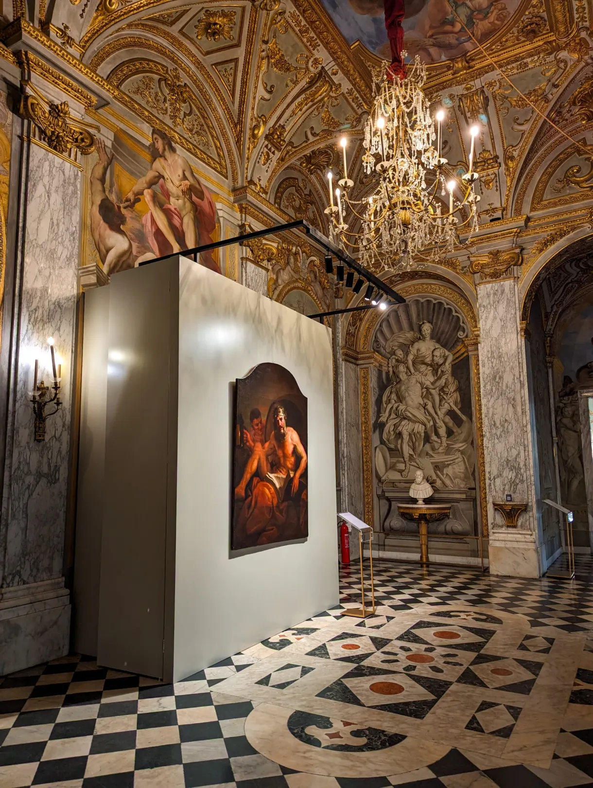 Tableau ancien accroché sur une cimaise dans une salle à lustre