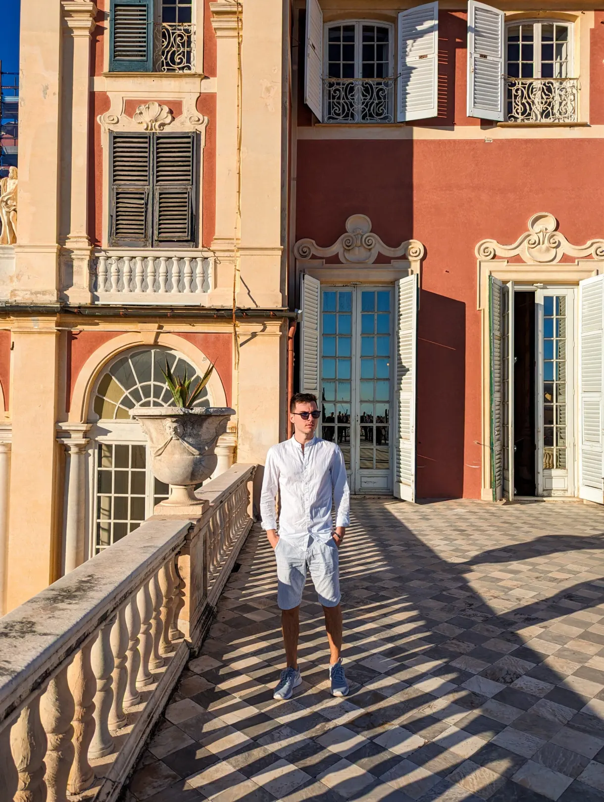 Homme marchant sur la terrasse à balustrade du palais rose