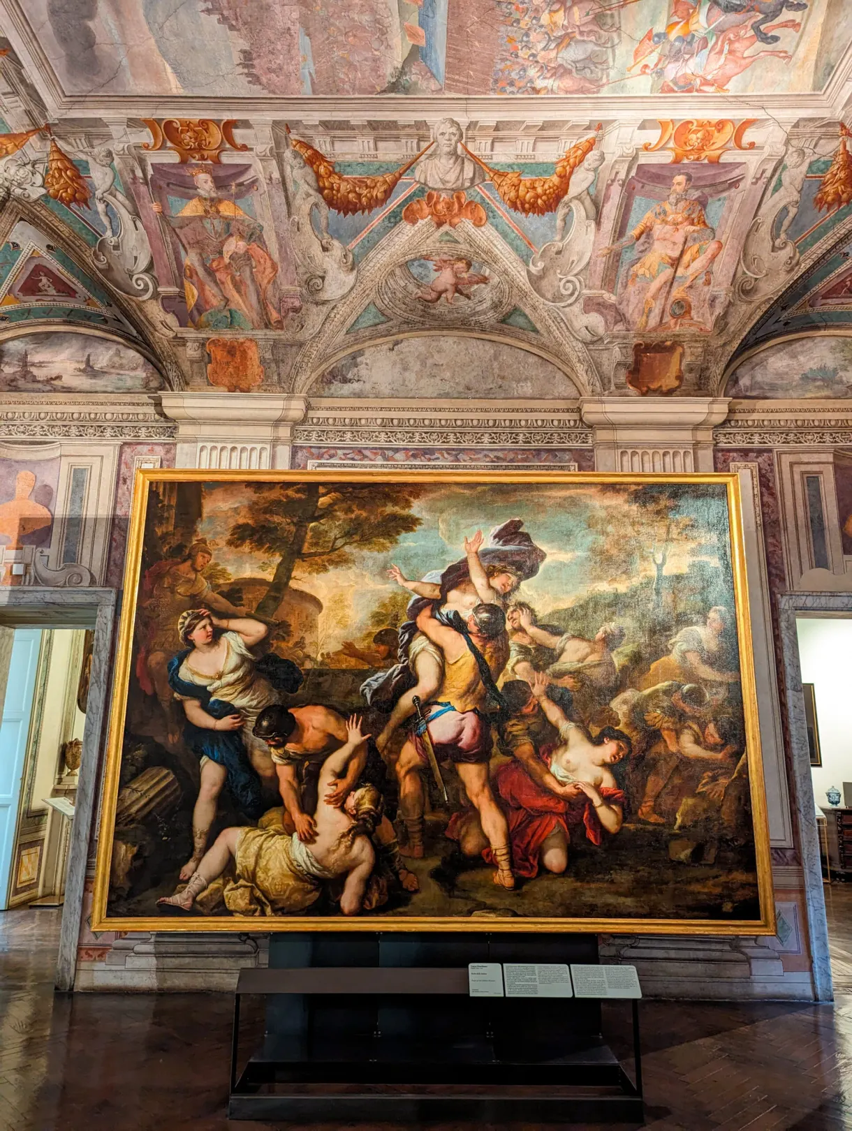 Grande toile de maître présentée sous un plafond à fresques
