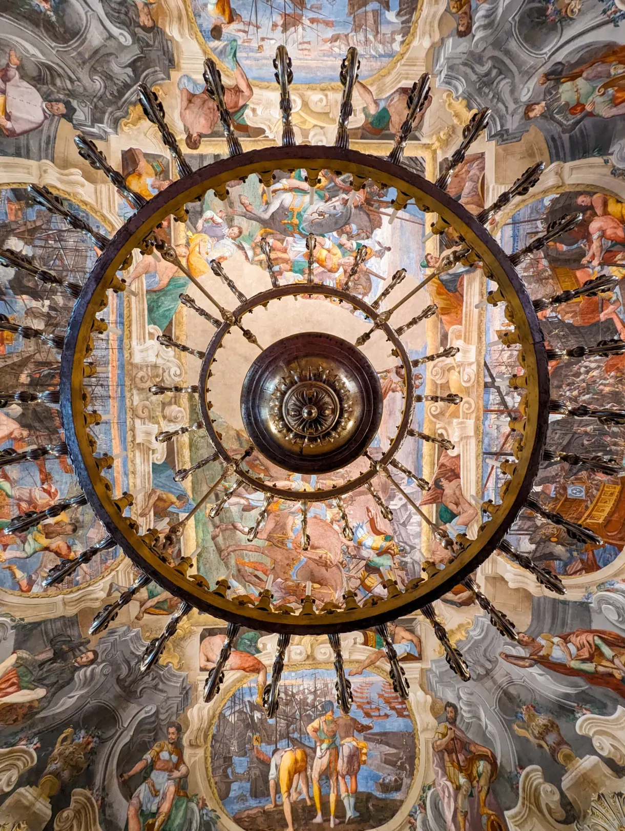 Lustre doré vu de dessous, sur fond de plafond peint