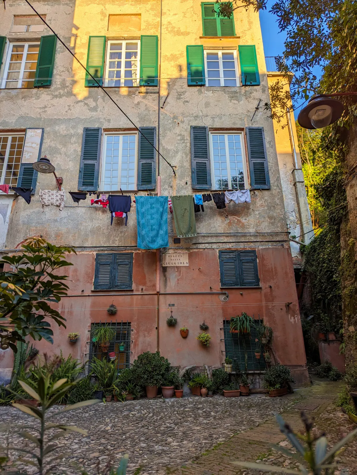 Linge étendu aux fenêtres d'une façade à volets verts
