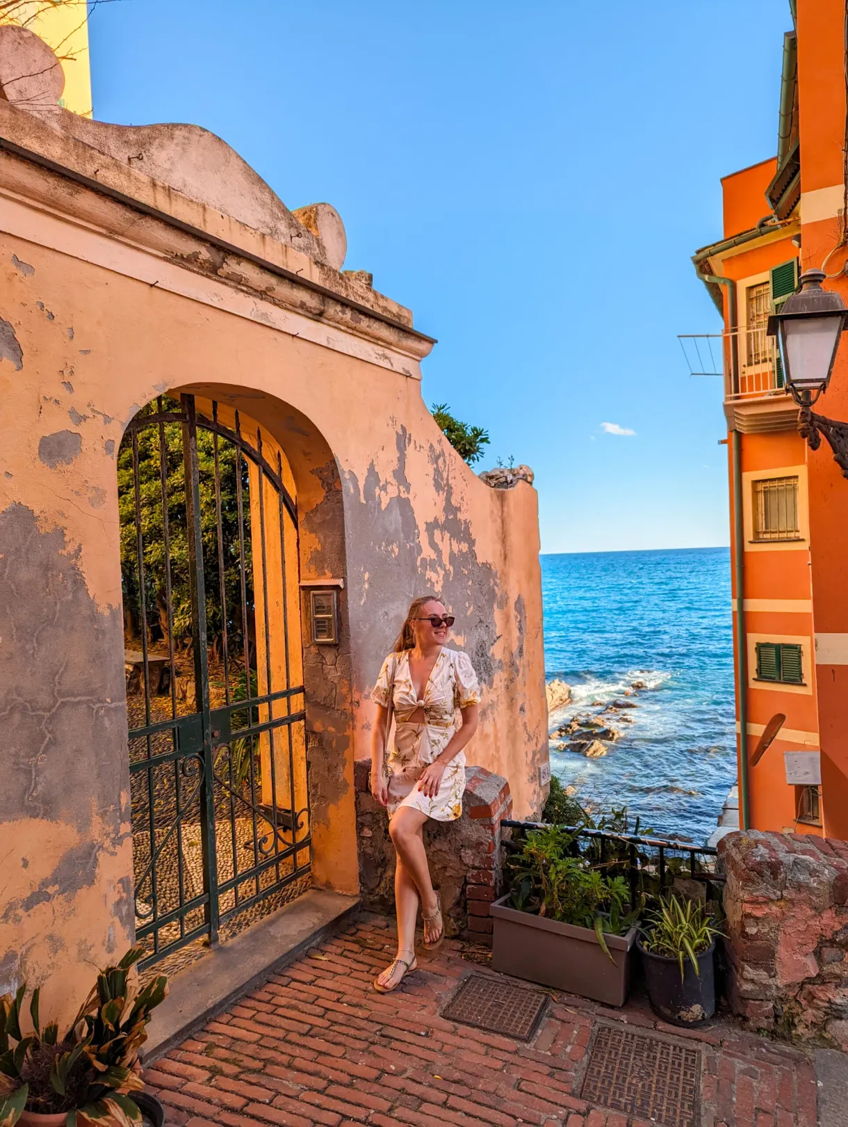 Femme sous un porche ancien ouvrant sur la mer et les maisons orange