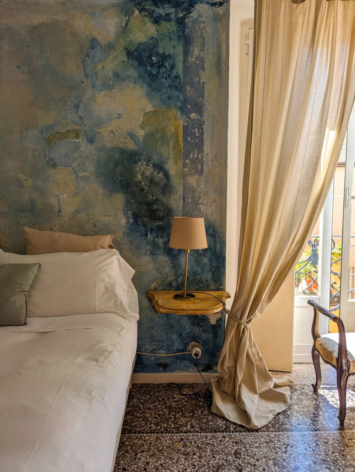 Chambre au mur peint de bleu et lit blanc près de la fenêtre