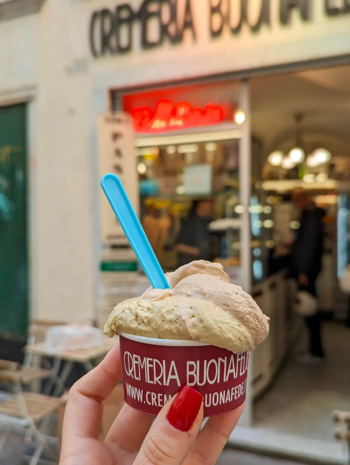 Pot de glace tenu à la main devant la vitrine d'une gelateria