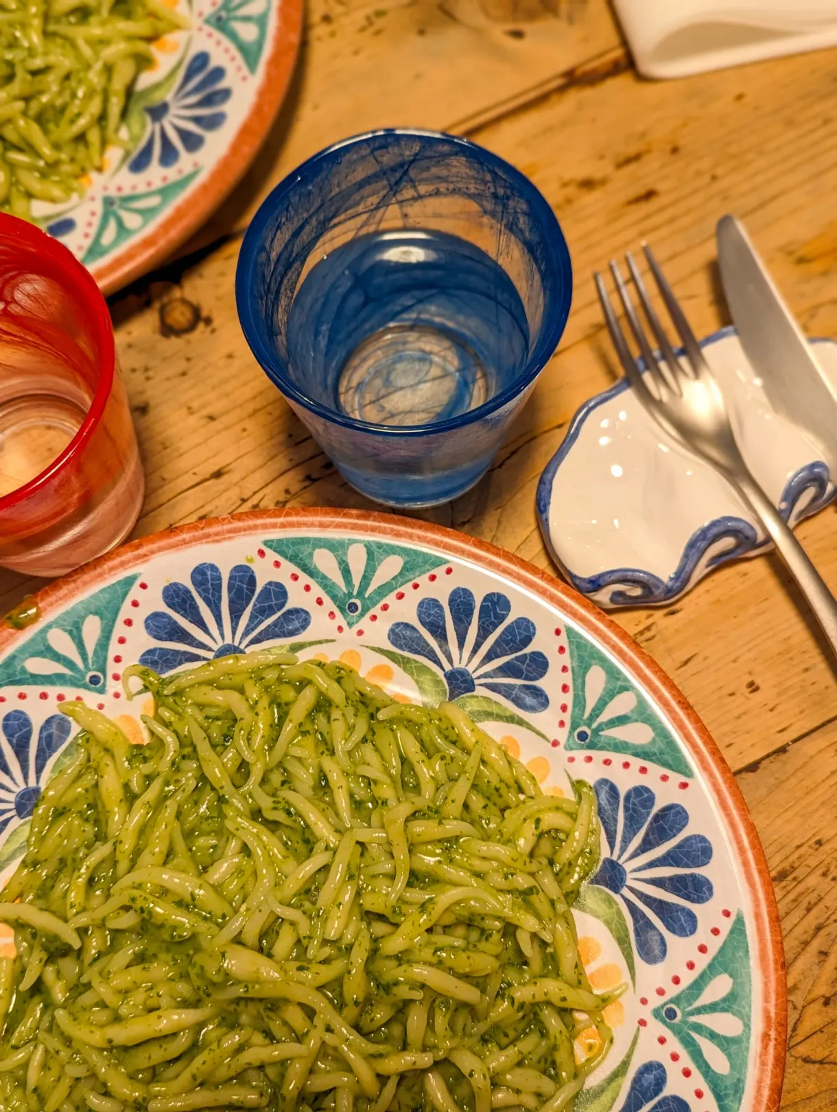 Trofie au pesto dans une assiette à motifs bleus sur table en bois