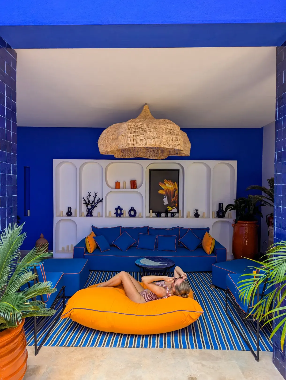 Salon bleu d'un riad à Marrakech, Marie allongée sur un grand pouf orange