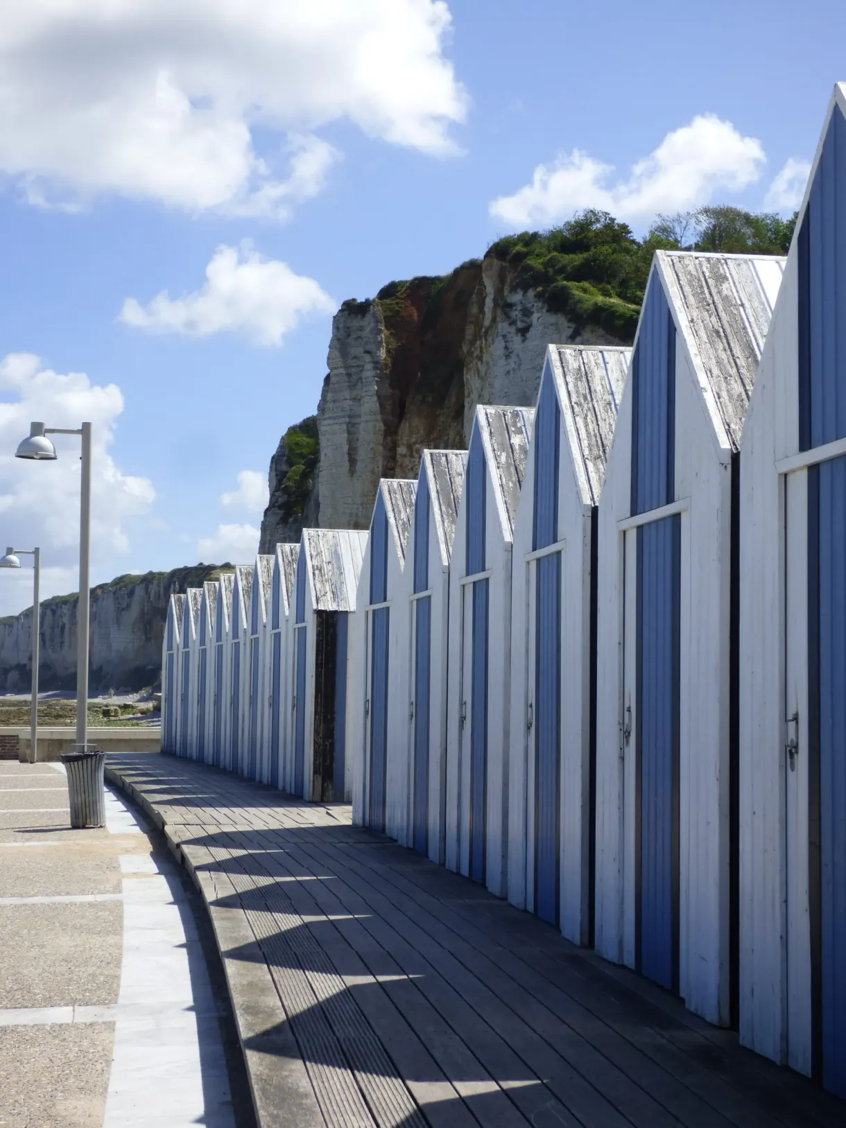 Rangée de cabines de plage blanches et bleues sous la falaise