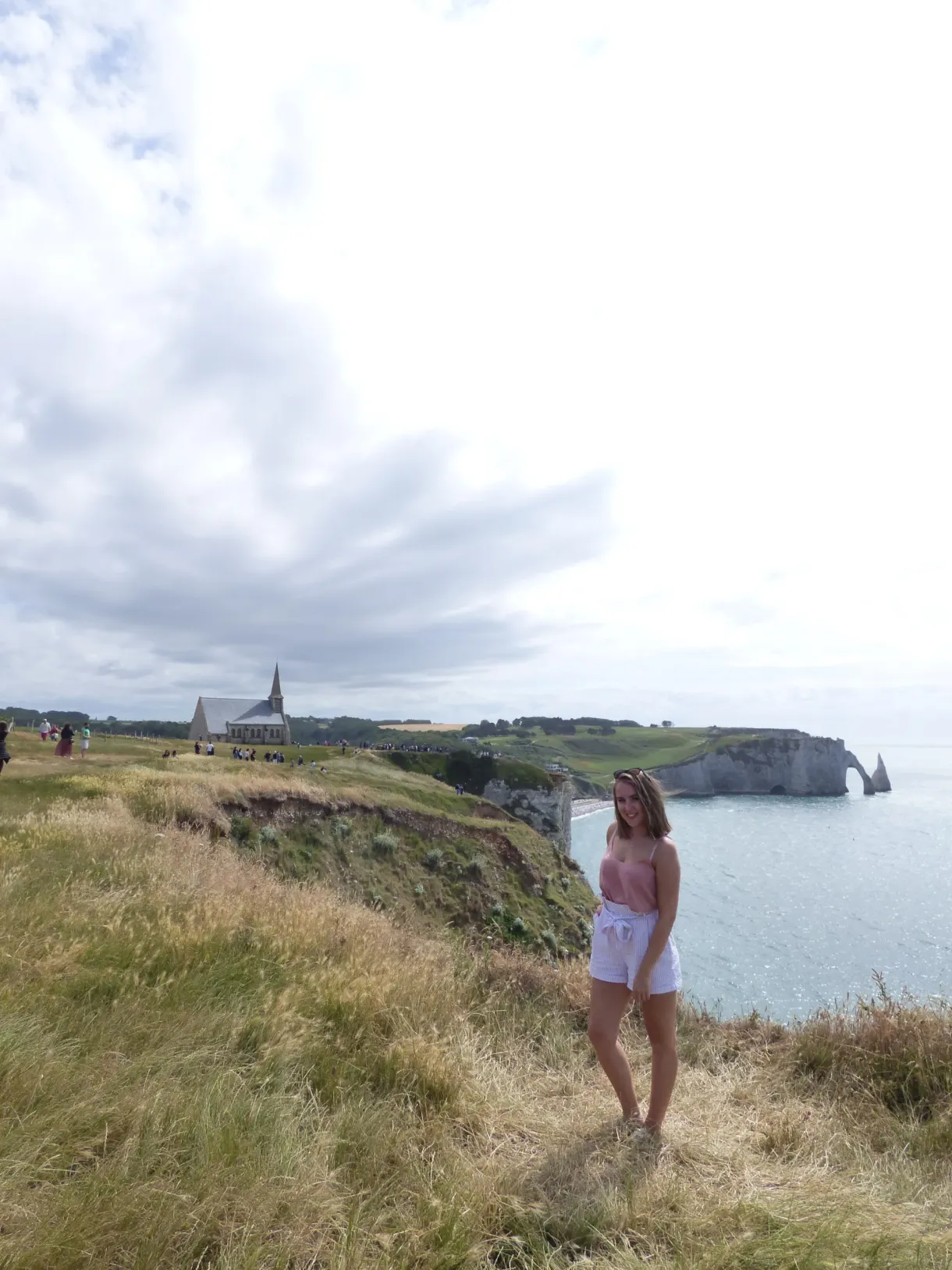Promeneuse sur le sentier des falaises, chapelle et arche au loin