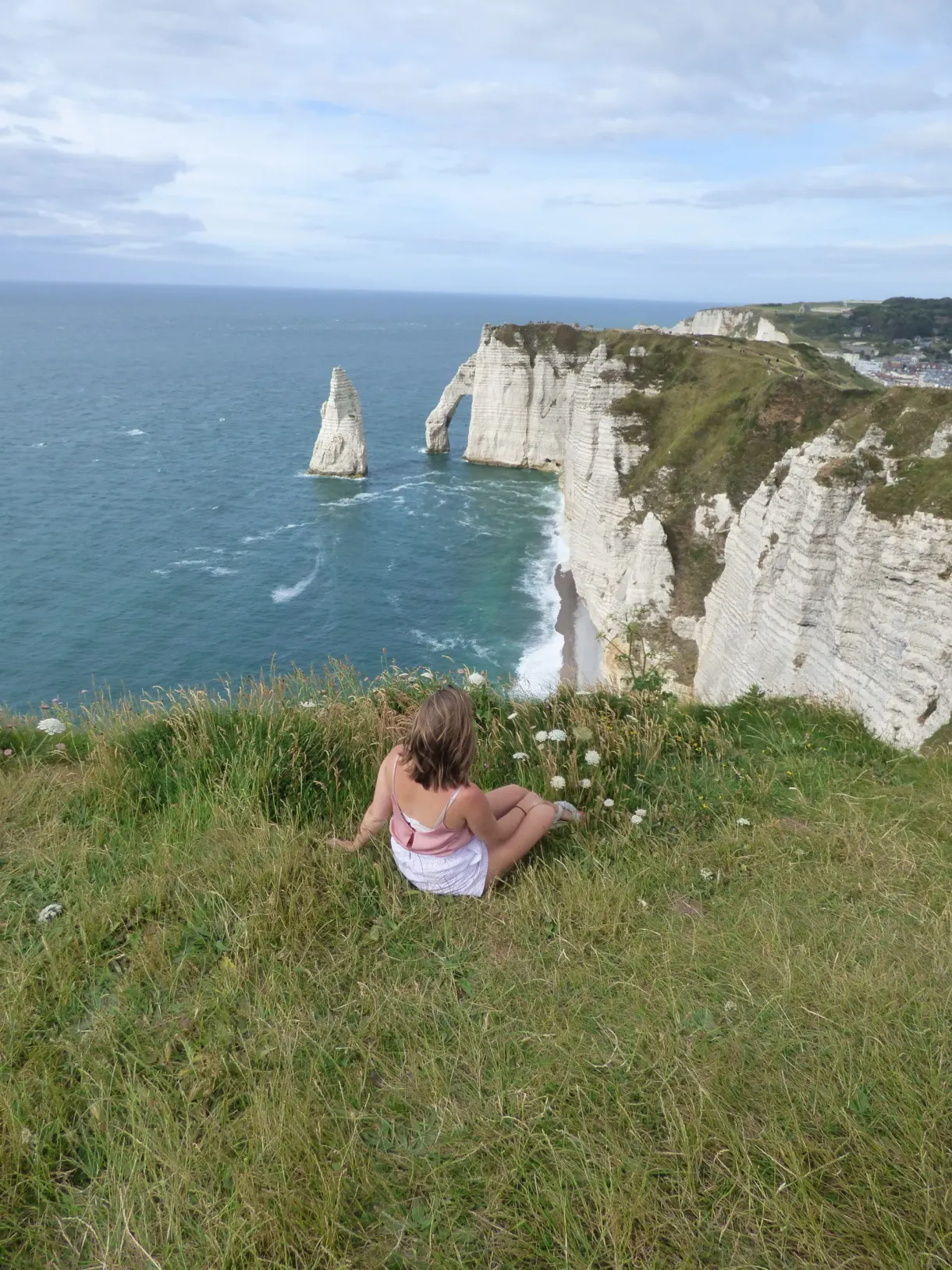 Randonneuse assise dans l'herbe face à l'aiguille et à l'arche