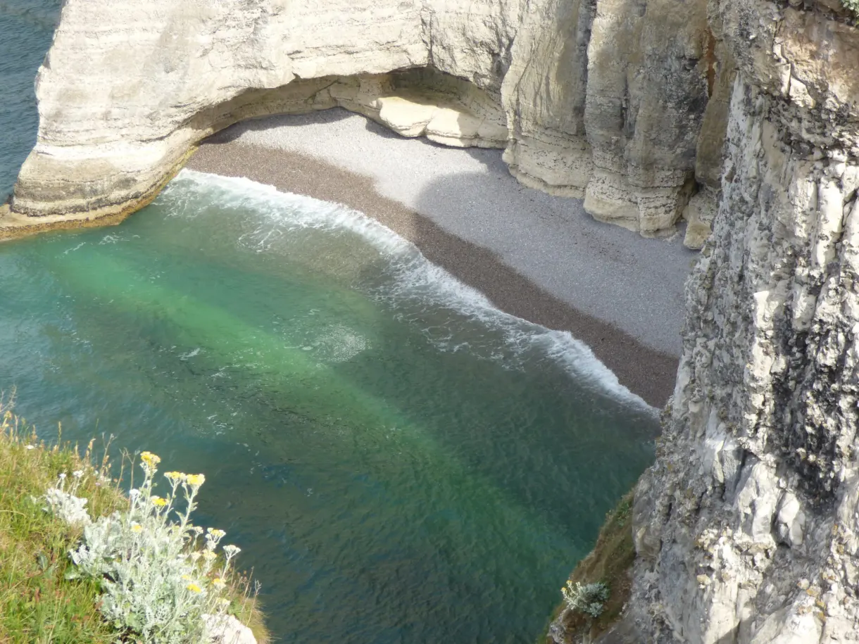 Crique aux eaux vertes et plage de galets sous l'arche