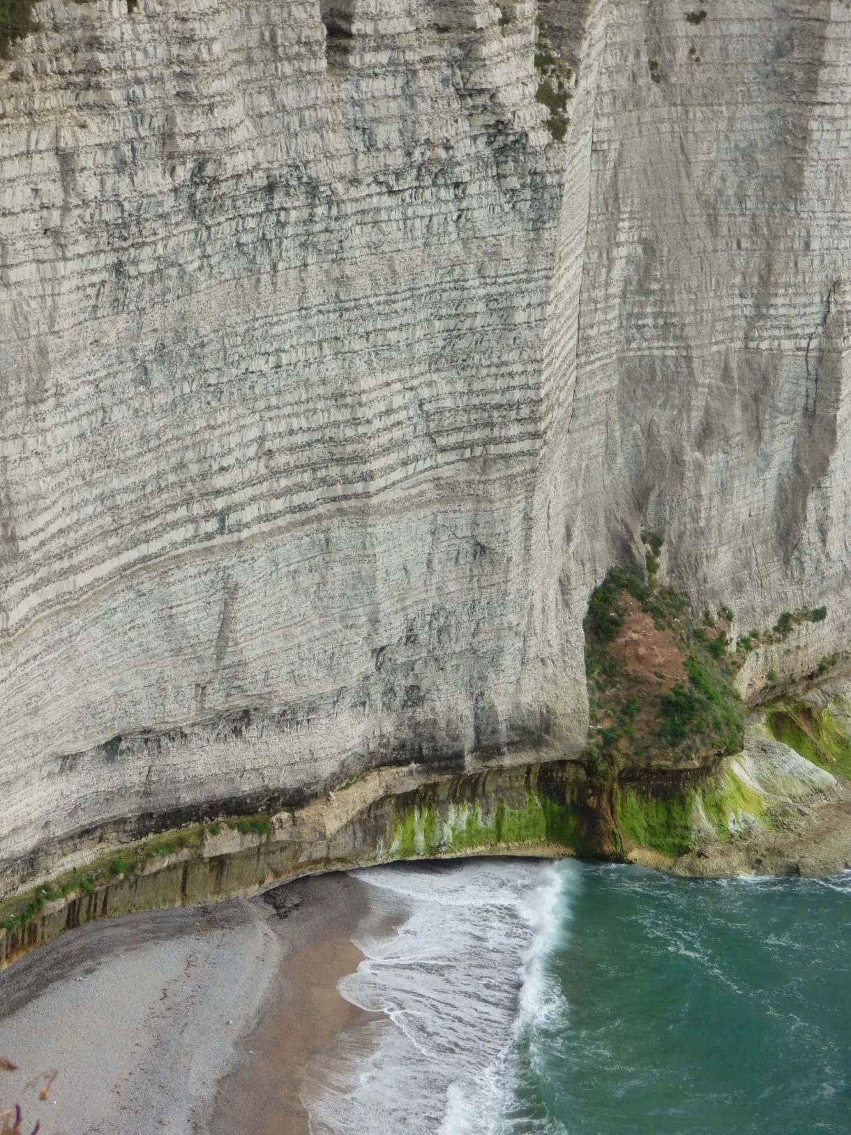 Paroi stratifiée de la falaise plongeant sur une petite plage