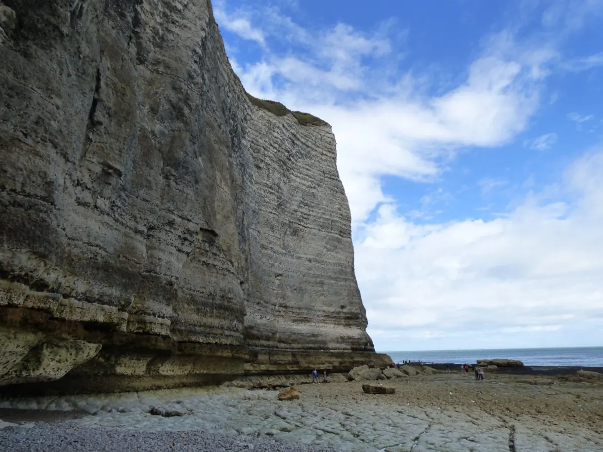 Mur de falaise dominant la plage de galets sous les nuages