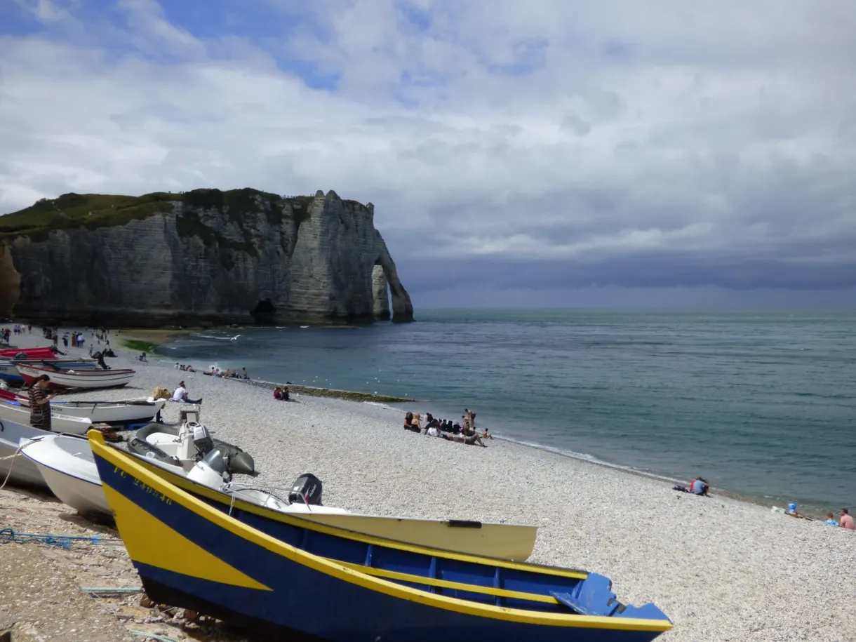 Barque bleue et jaune sur les galets face à l'arche