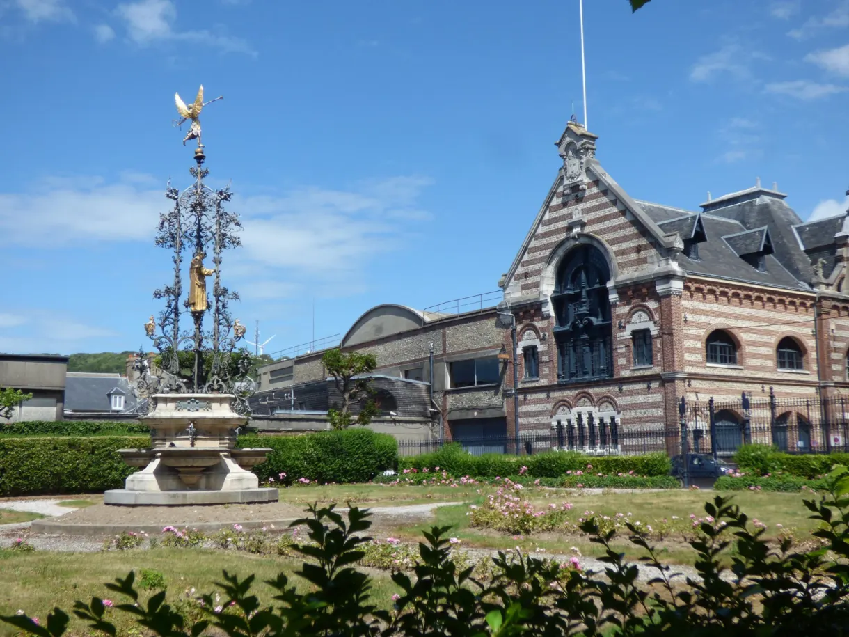 Jardin fleuri et flèche ouvragée devant le palais Bénédictine
