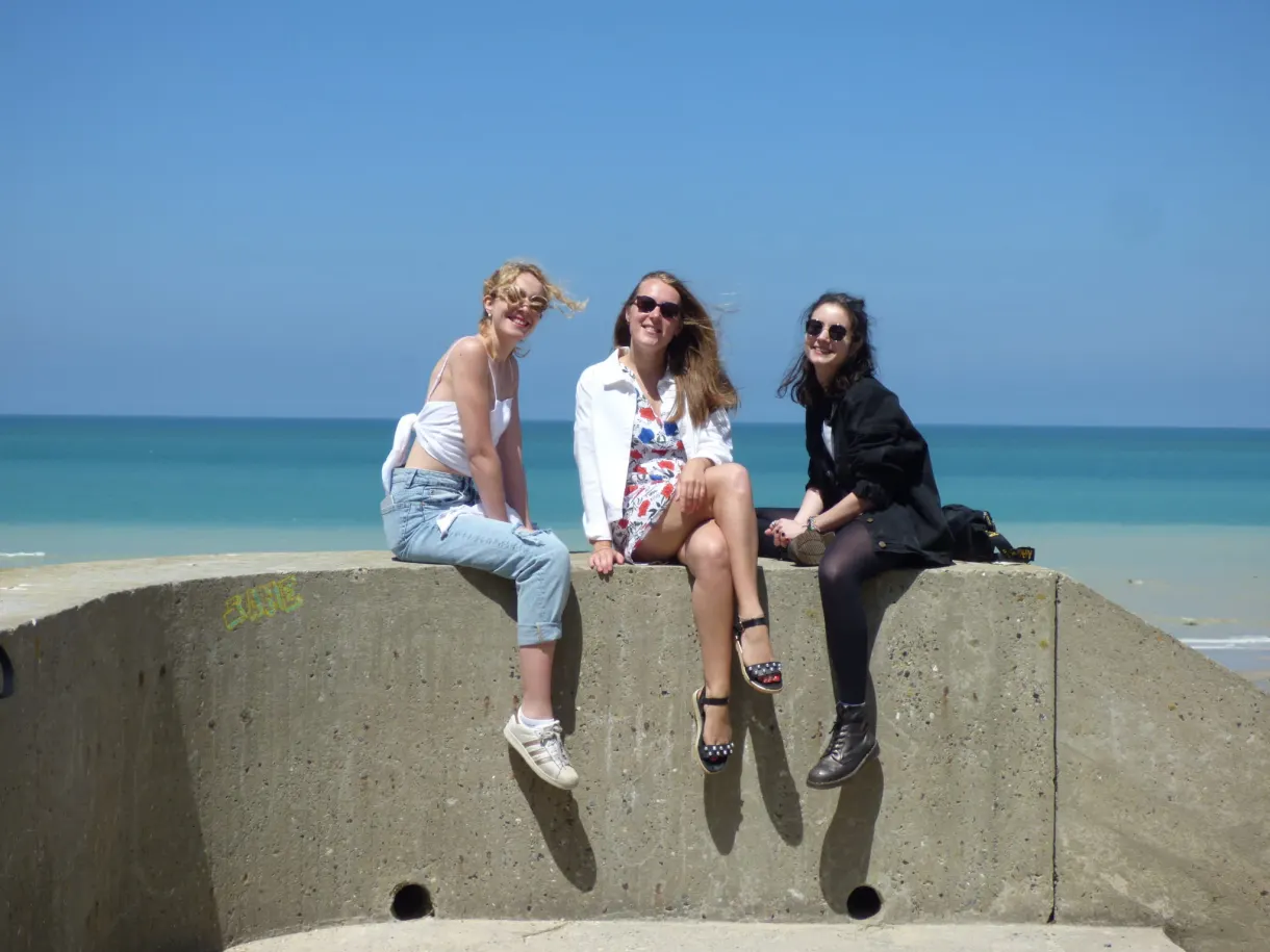 Trois amies assises sur un bloc de béton face à la mer