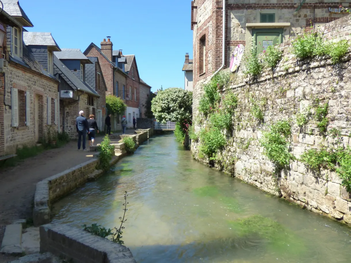 Ruisseau canalisé entre des murets de pierre et des maisons anciennes