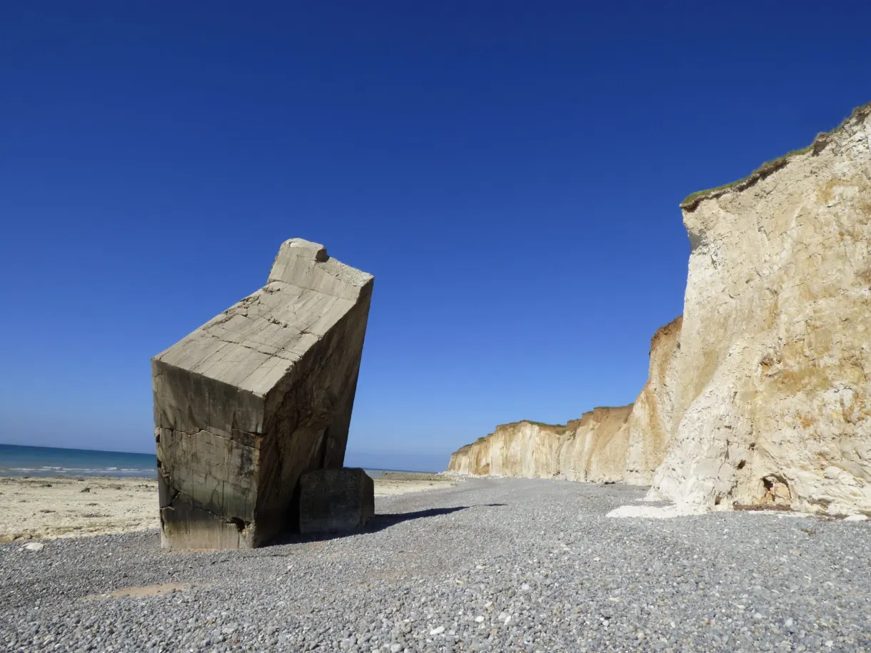 Bloc de blockhaus renversé sur les galets au pied de la falaise