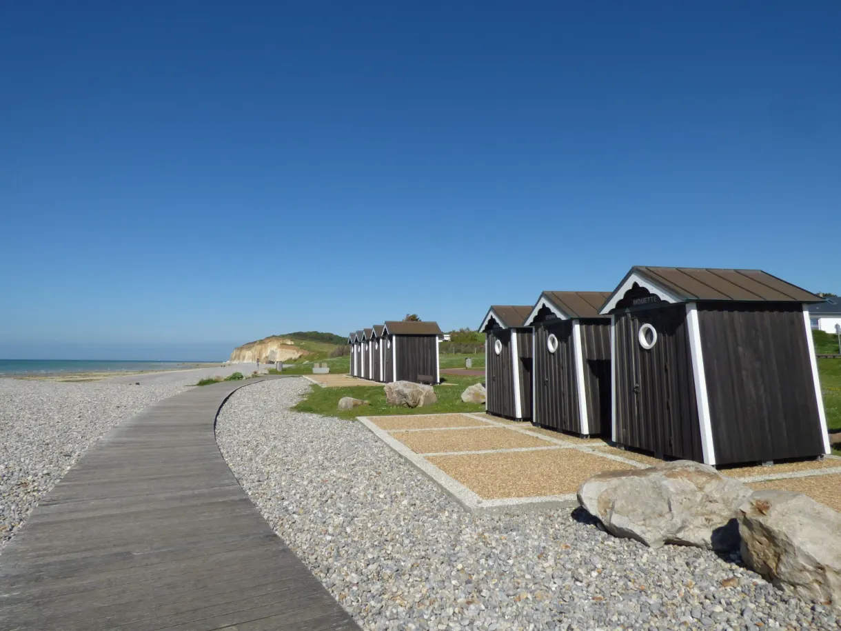 Cabines de plage en bois alignées le long du cheminement, en fin de journée