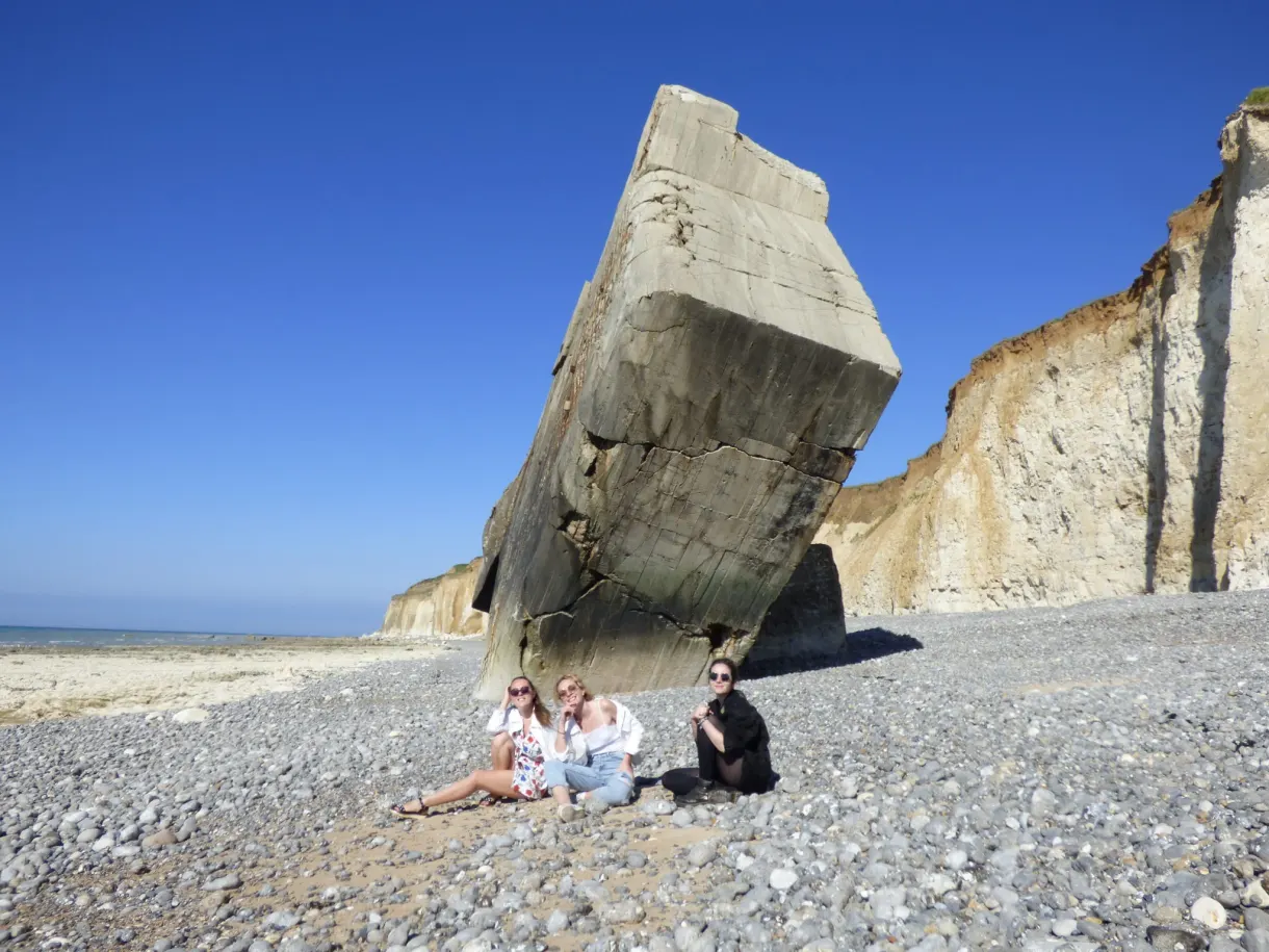 Trois amies assises sous un blockhaus basculé sur la plage