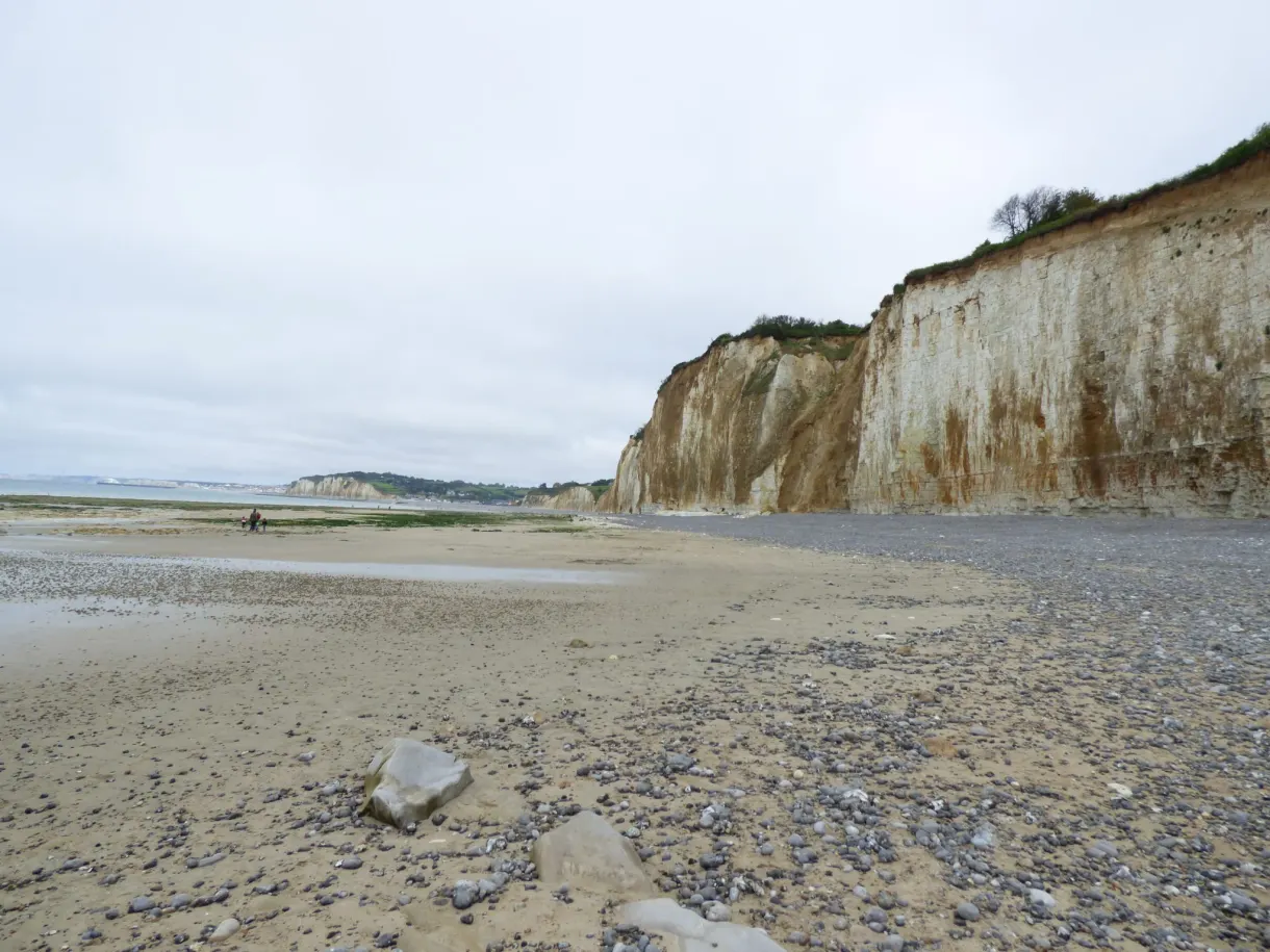 Plage de galets et falaise claire sous un ciel couvert