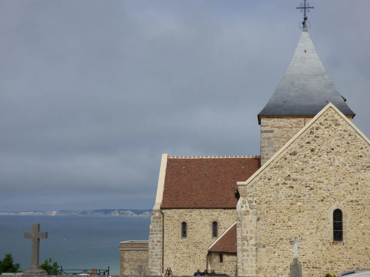 Église de pierre et sa croix de calvaire au-dessus de la mer