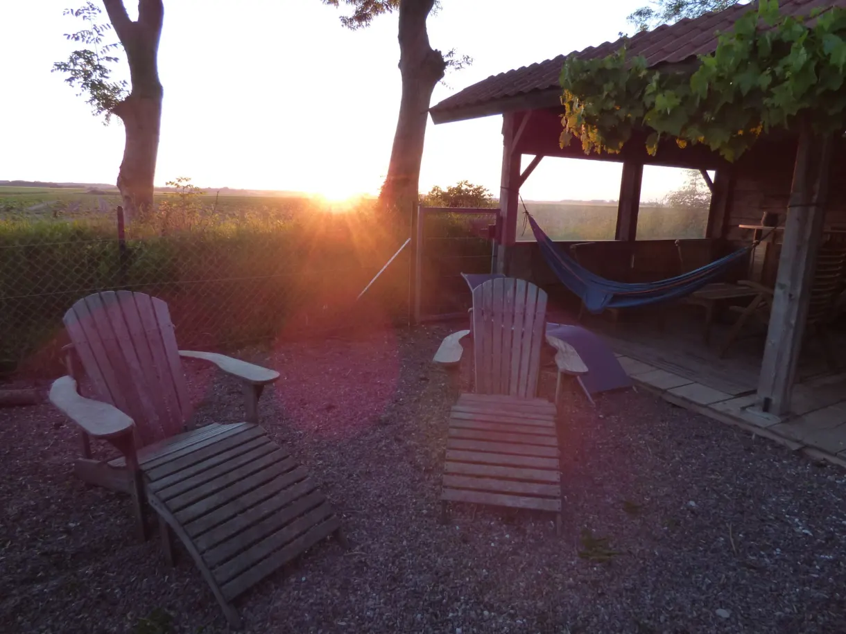 Fauteuils de jardin et pergola face au soleil couchant