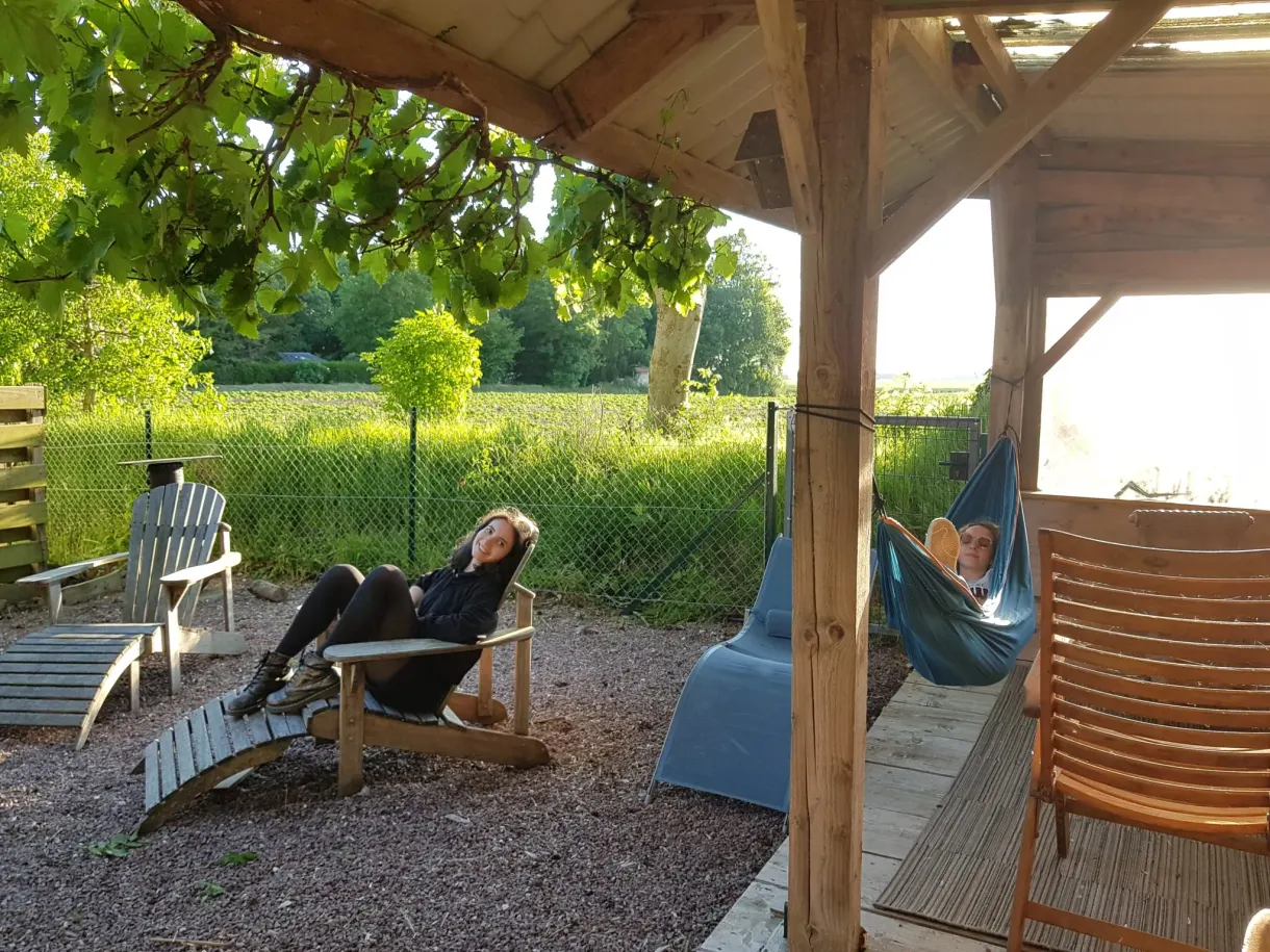 Femme allongée sous la pergola en bois près d'un hamac