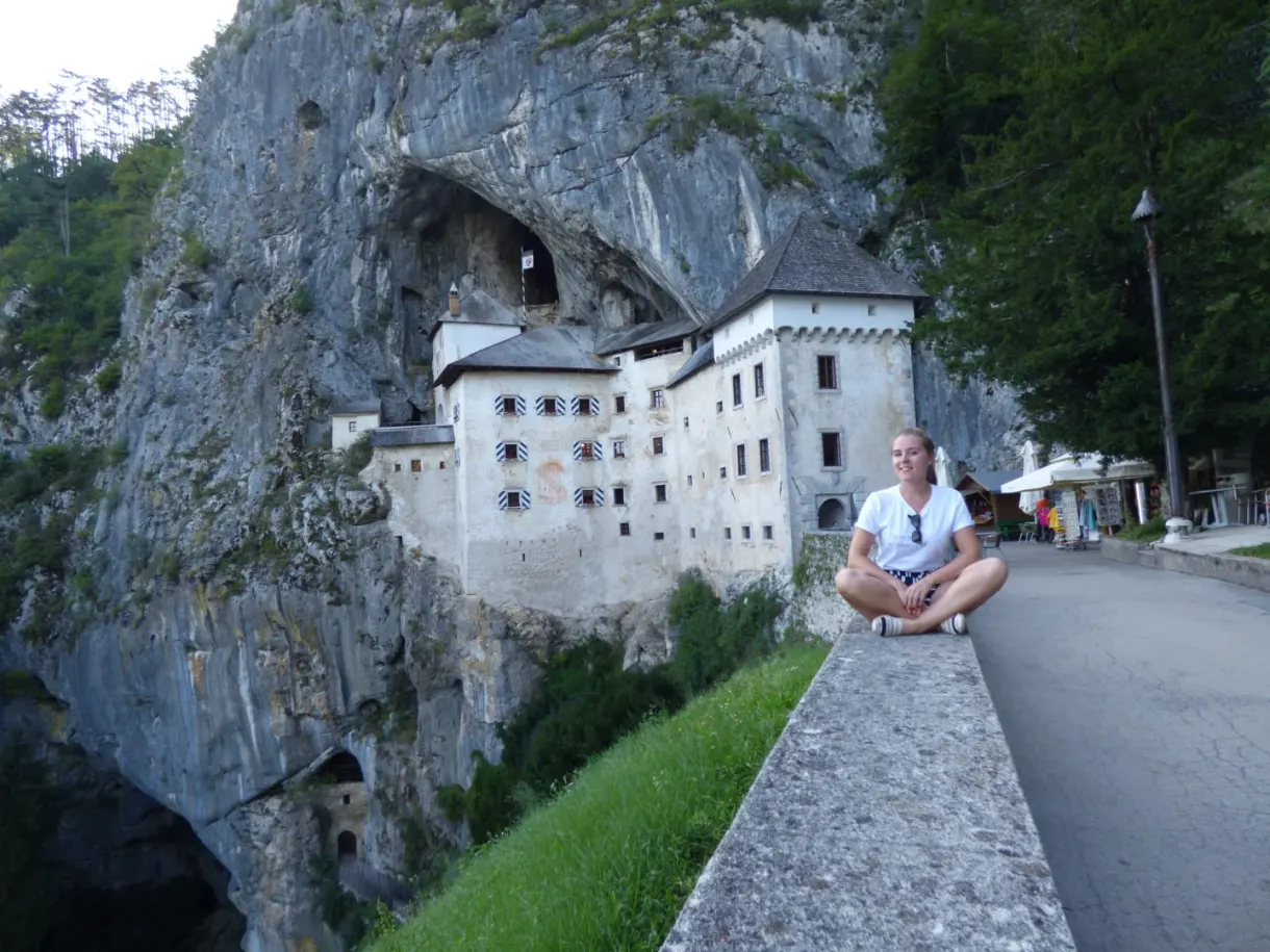 Woman sitting on a low wall along the road leading to the castle