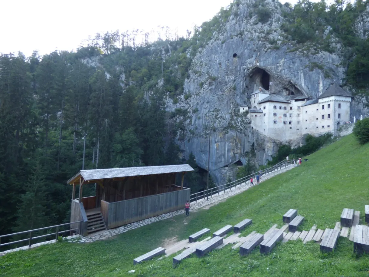 Castle in its cave overlooking a meadow and wooden bleachers