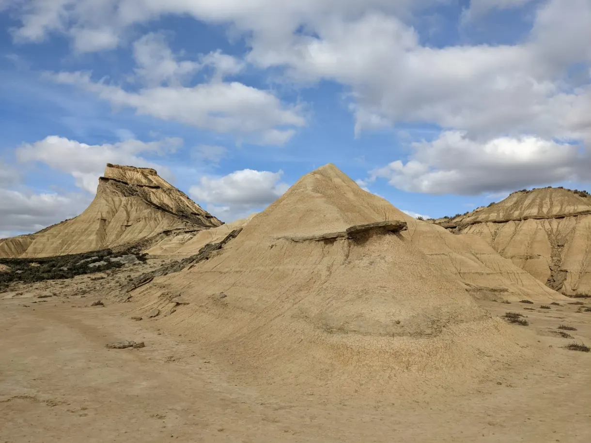 Buttes coniques d'argile claire sous un ciel moutonné
